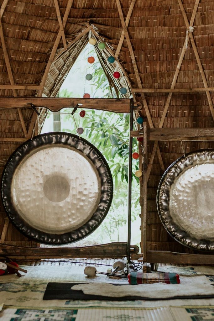 Interior view of a bamboo hut featuring traditional gongs used for sound healing and meditation.
